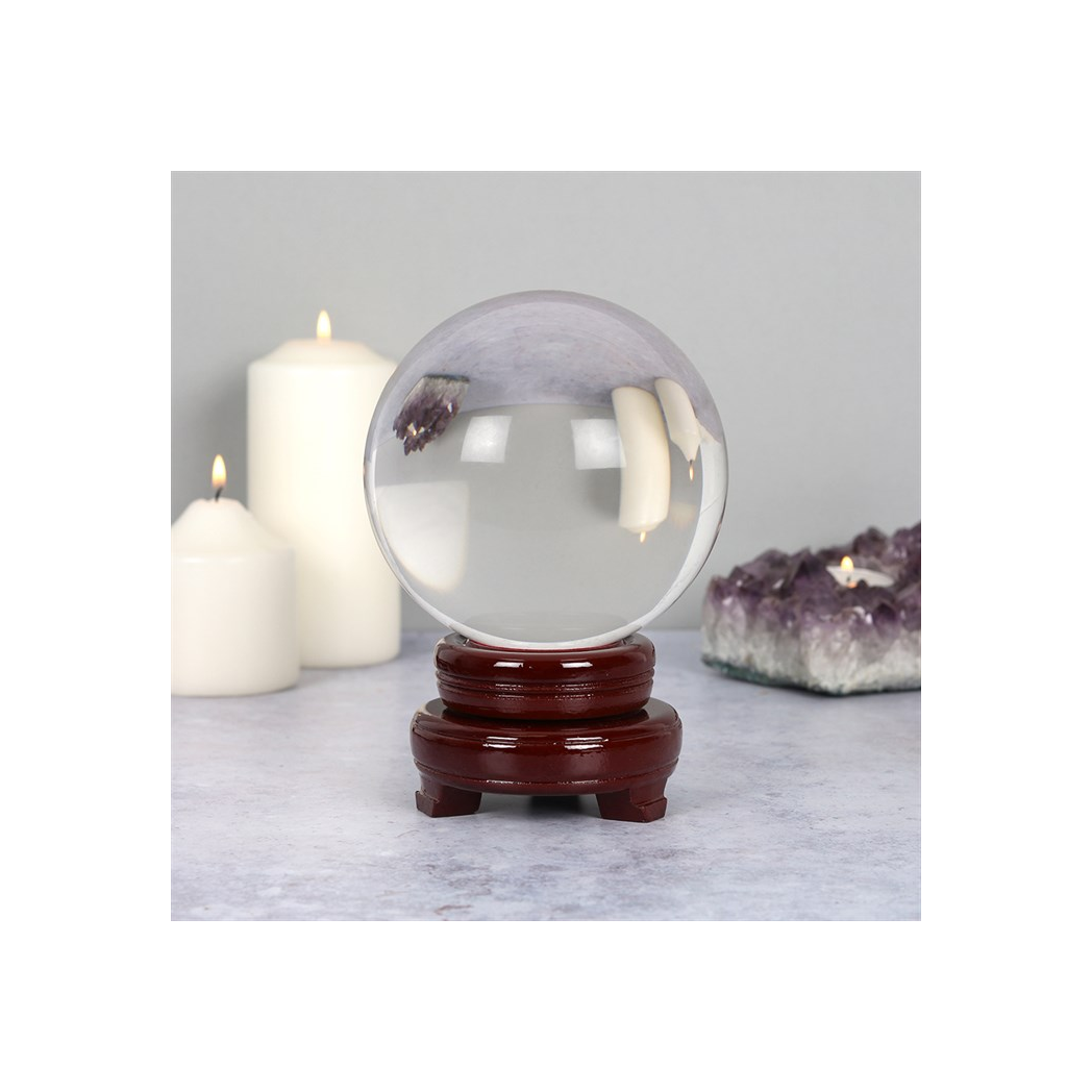 Crystal ball on wooden stand with candles an crystals in background