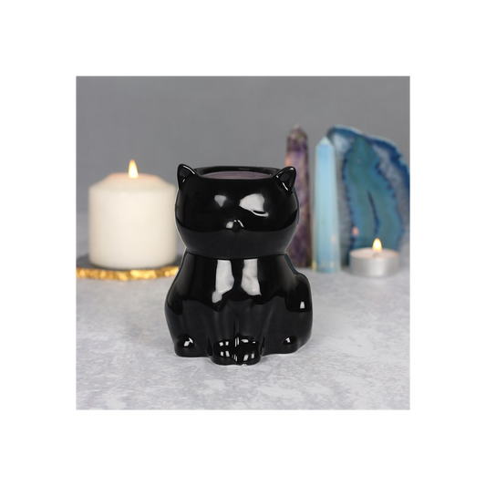 Black cat-shaped candle holder on a gray surface with candles and crystals in the background.