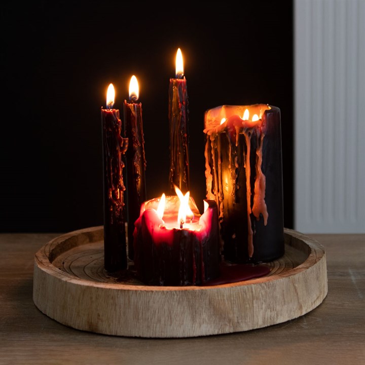 Set of five candles with different heights on a wooden base against a dark background