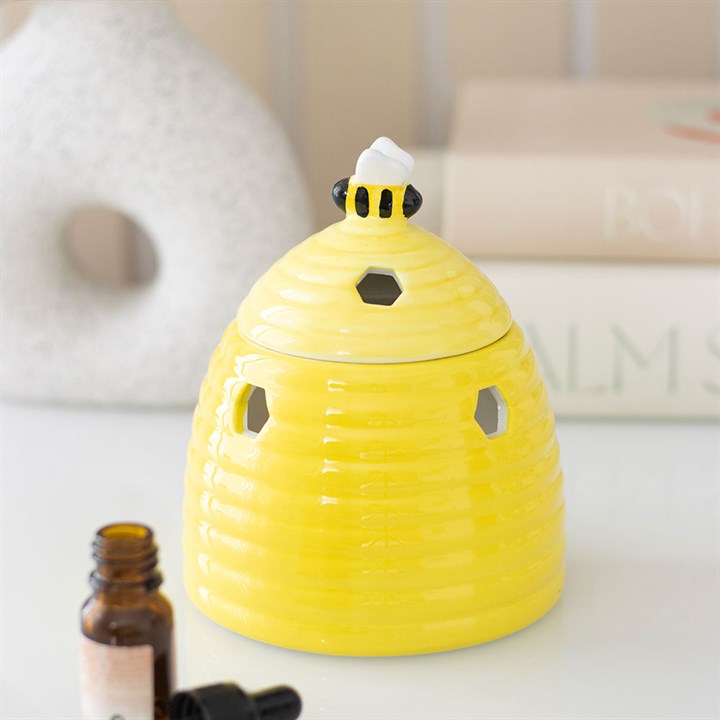 Yellow bee-shaped diffuser on a white surface with a bottle of essential oil.