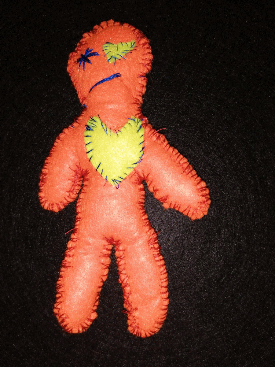 Handmade orange poppet with a yellow heart and eye and a blue stitched eye and mouth