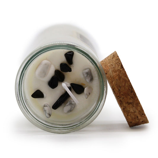 Candle in a glass jar with decorative stones on a white background