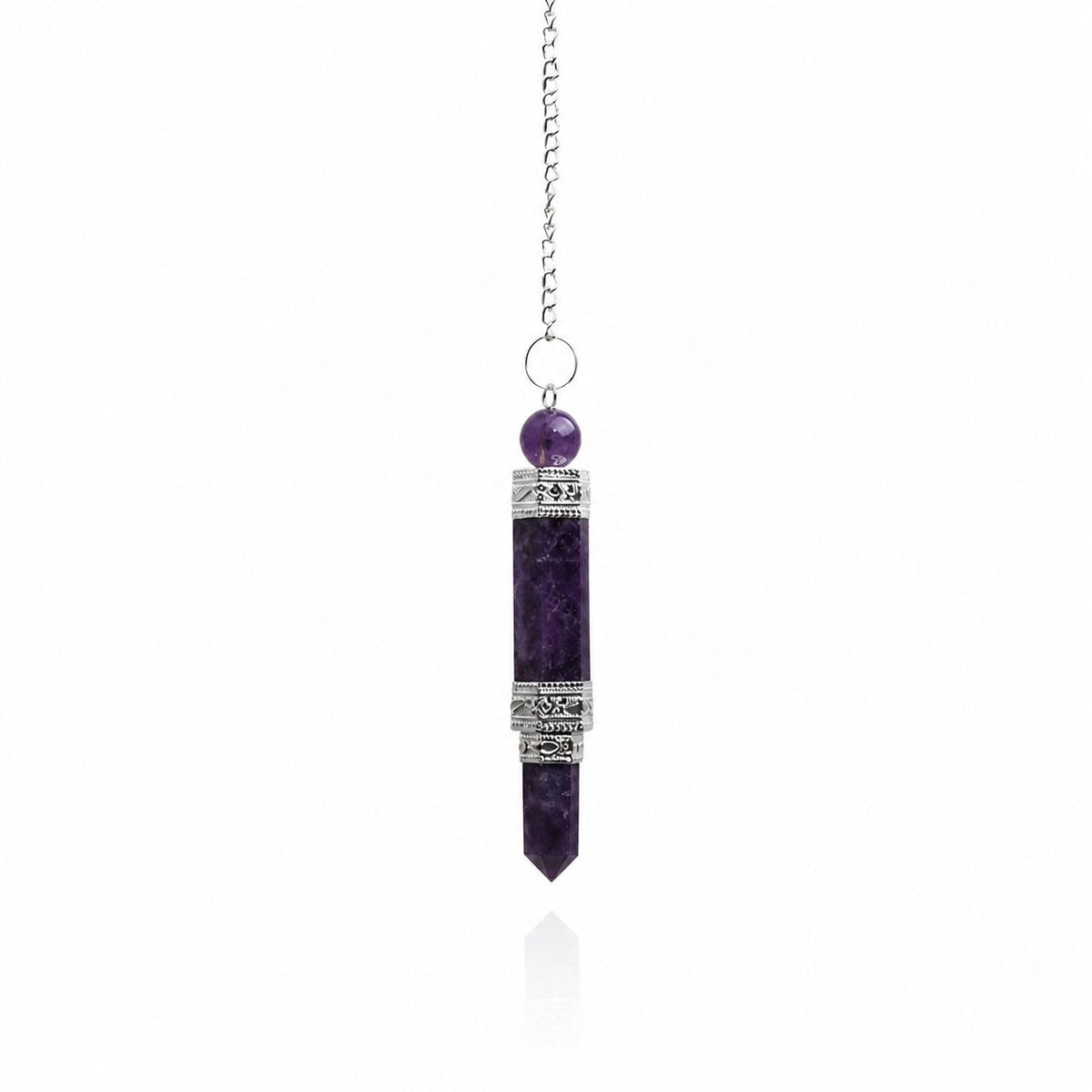 A silver-toned pendant necklace featuring a vertical amethyst crystal point pendant with decorative silver bands, a small round purple bead, and a delicate silver chain, shown against a white background with a soft reflection.