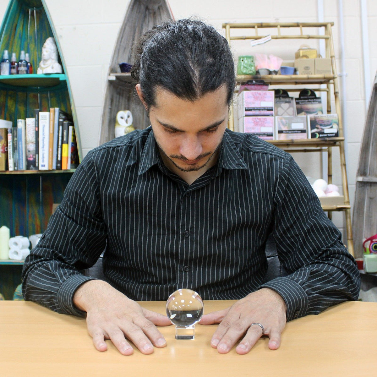 Man interacting with a crystal ball on a table in a room with shelves and decor.