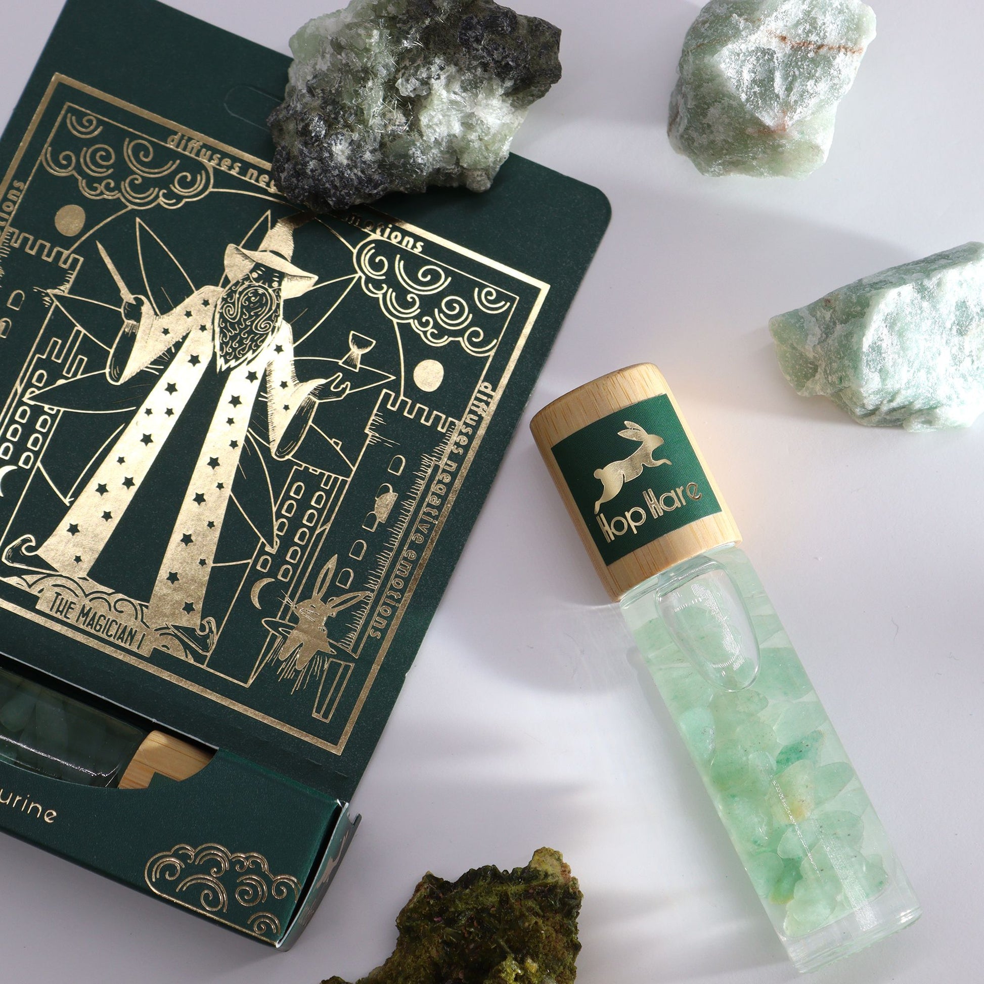 Green bottle with cap, tarot card, and crystals on a white background
