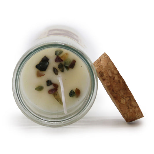 Candle in a glass jar with decorative stones and a cork lid on a white background