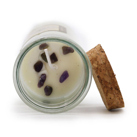 Candle in a glass jar with purple stones on a white background