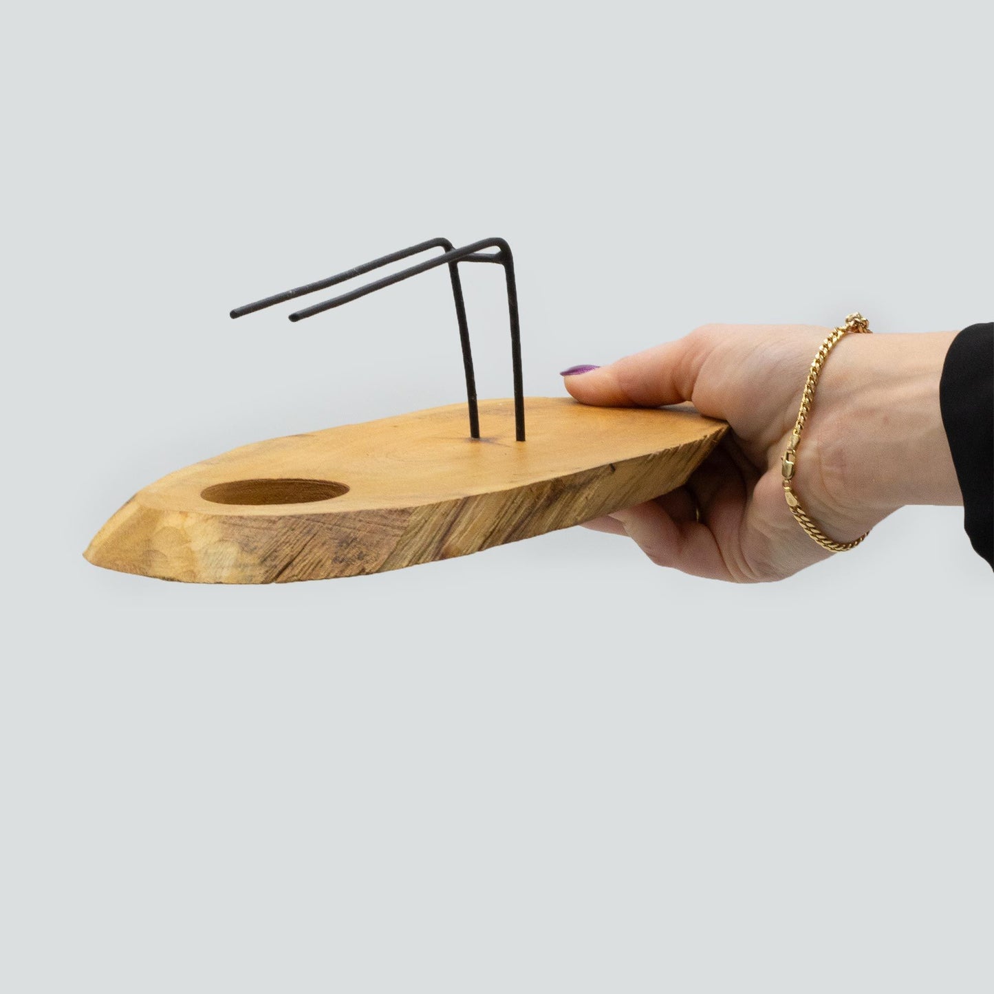Hand holding a Palo Santo Heater  handcrafted  from Natural Gamel wood with metal support for holding a smudge stick and an indentation for a tea light