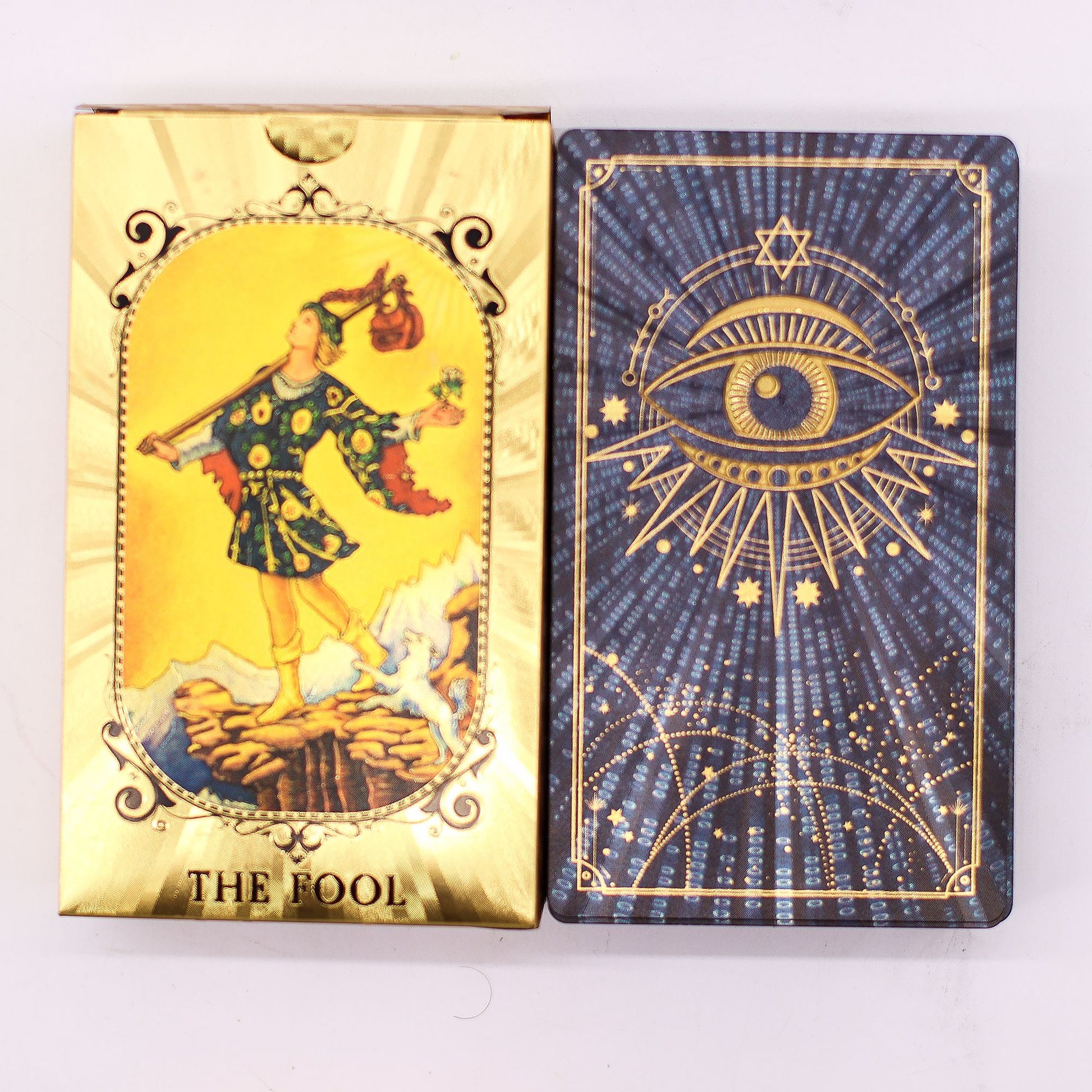 Two tarot cards, 'The Fool' on gold and 'Eye of Providence' on blue, on a purple fabric background.