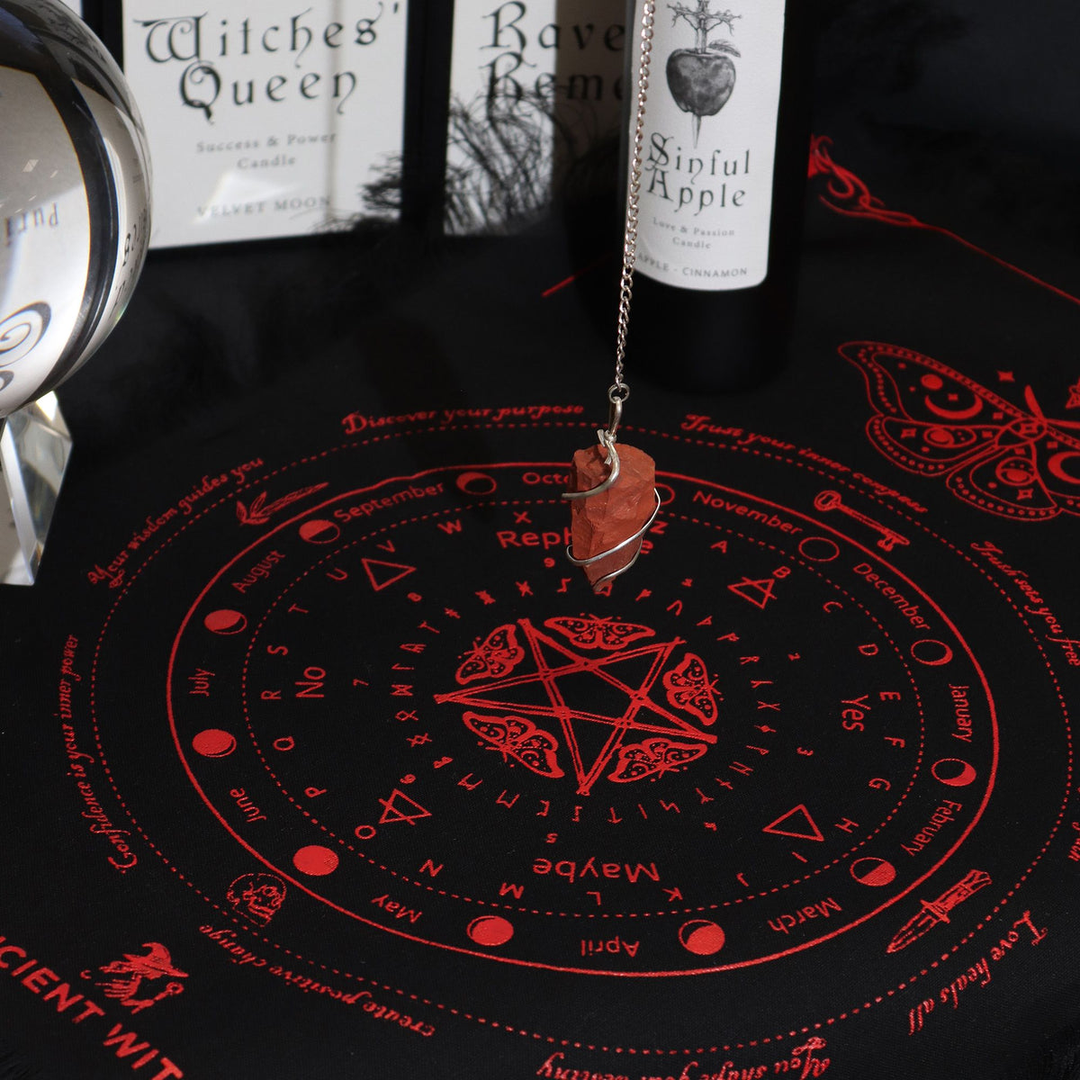 Black cloth with red astrological design showing a hanging crystal and candles