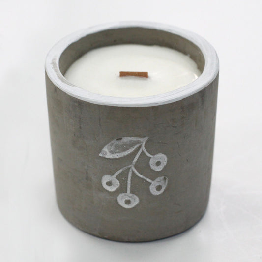 Candle in a concrete holder with a leaf design on a white background