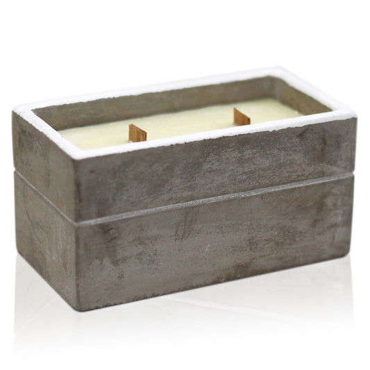 Rectangular concrete candle holder with a white candle inside on a white background