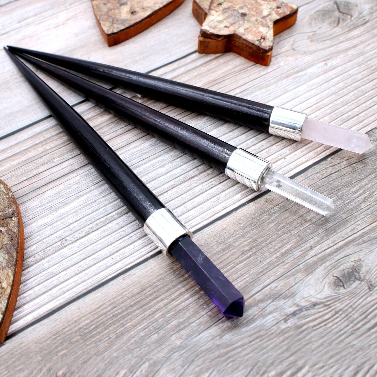 Three black and silver artistic tools on a wooden surface