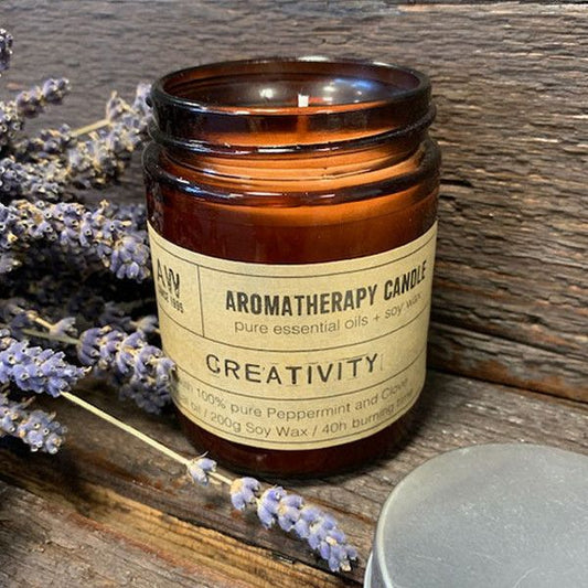Aromatherapy candle labeled 'Creativity' with lavender flowers on a wooden surface