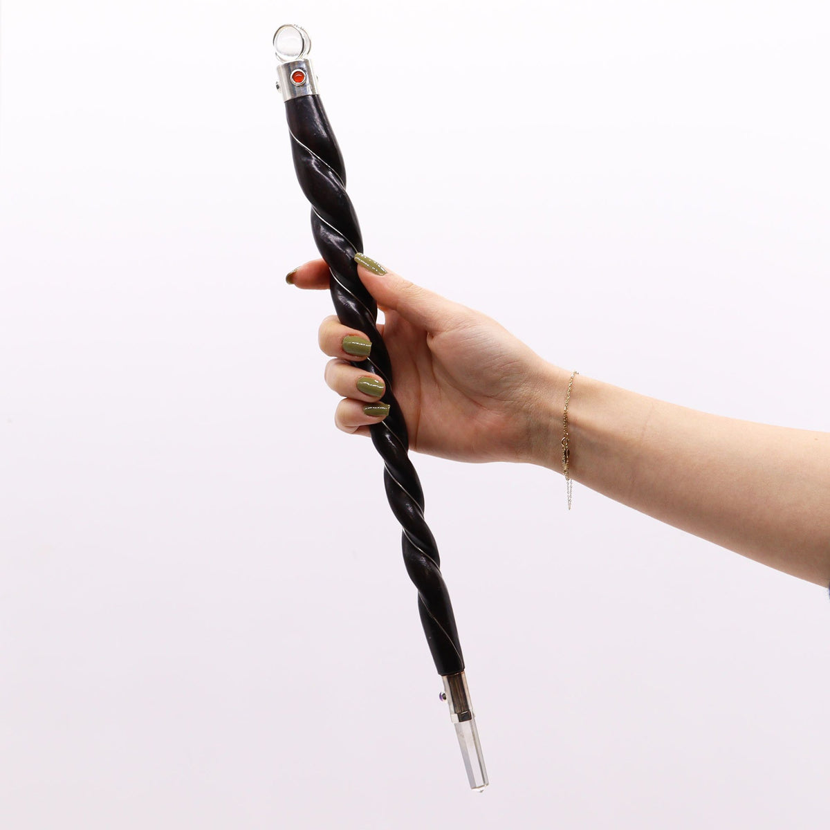 Hand holding a black and silver twisted cane against a white background