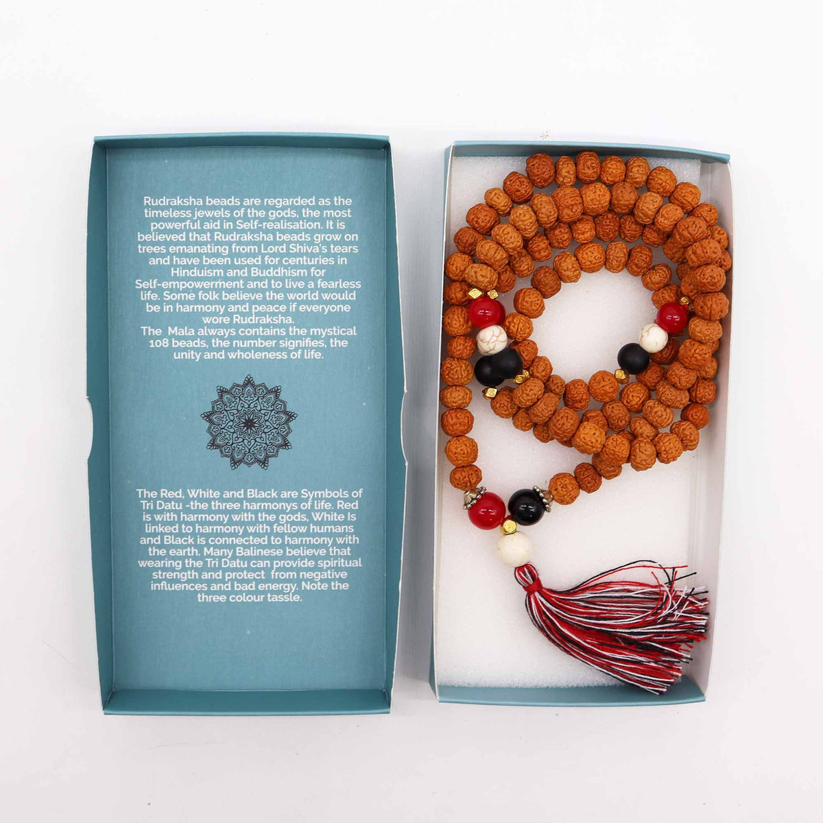 Mala beads with a tassel in a box, accompanied by a descriptive card on a white background